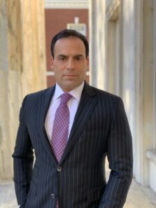 Man in pinstripe suit standing outside building.