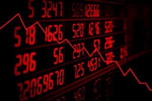 Red stock market board showing falling values and a downward trend graph.