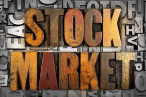 Wooden block letters spelling 'Stock Market' on a dark background.