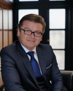 Professional man in suit and glasses sitting indoors.