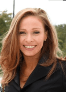 Smiling woman with long light brown hair outdoors.