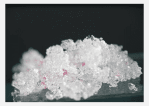 Close-up of granular white salt crystals with a few pinkish particles.