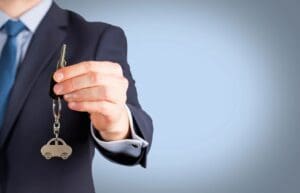 A person in a suit holding a set of house keys.