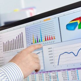 Hand pointing at financial charts on monitor