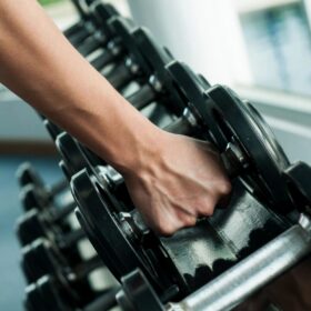 Hand grabbing dumbbell from gym rack